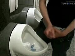 Een rondborstige brunette geeft oraal en slikt sperma in een openbaar toilet