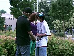 Doi bărbați fac sex cu o tânără blondă în public în timp ce mașini și camioane privesc în acest videoclip de sex în grup