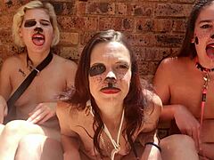 Tres mujeres desnudas se involucran en juegos de lengua kinky al aire libre